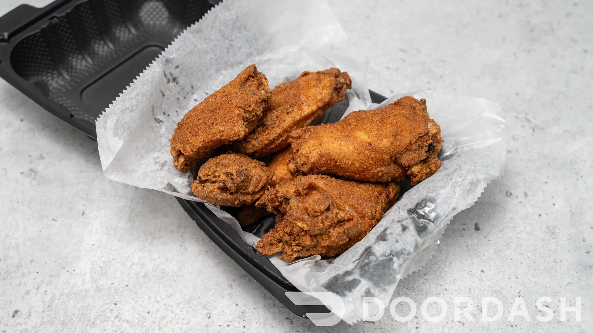 Crispy fried chicken wings in a takeout container