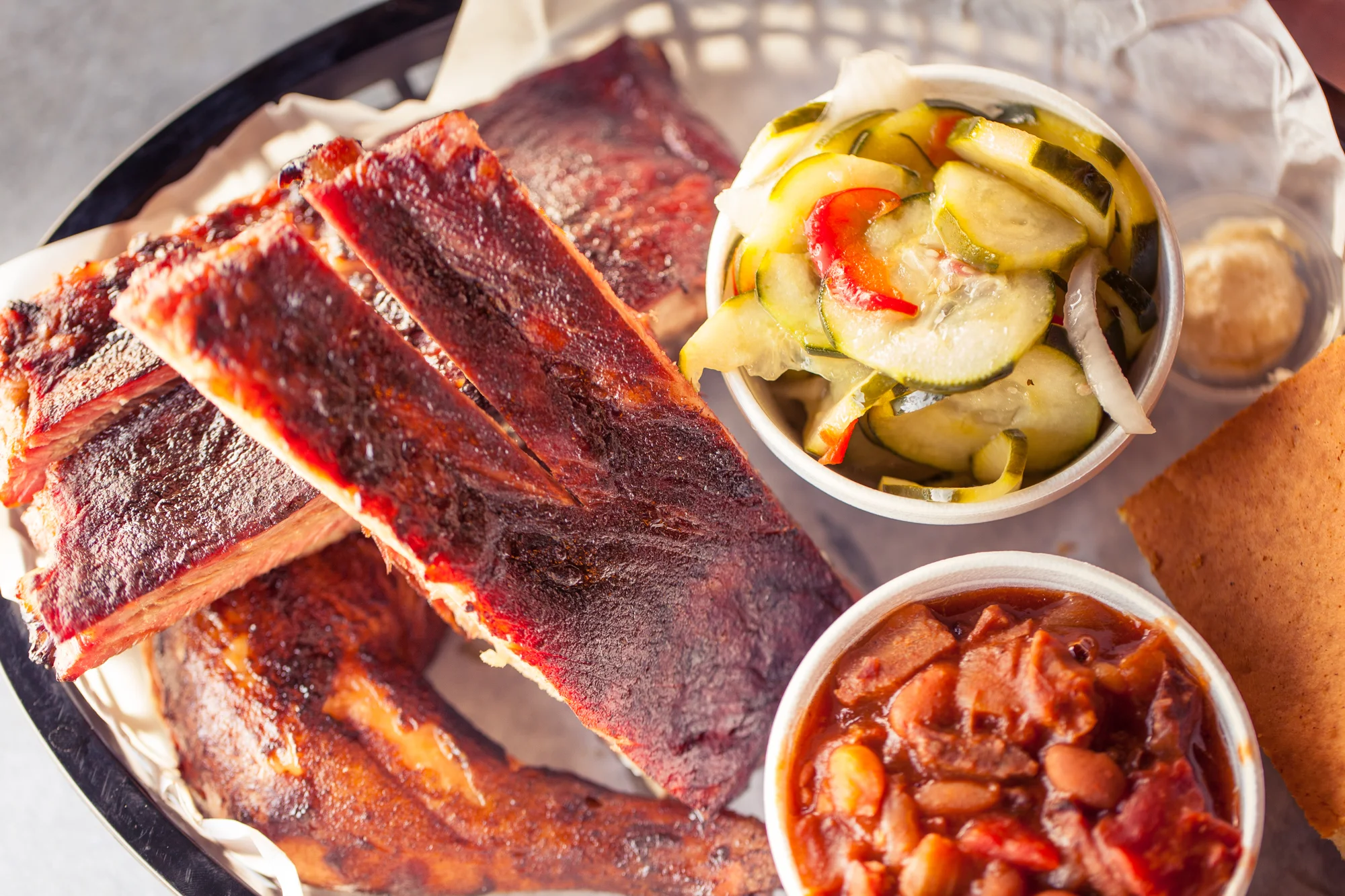 Smoky barbecue ribs with sides of pickles and baked beans