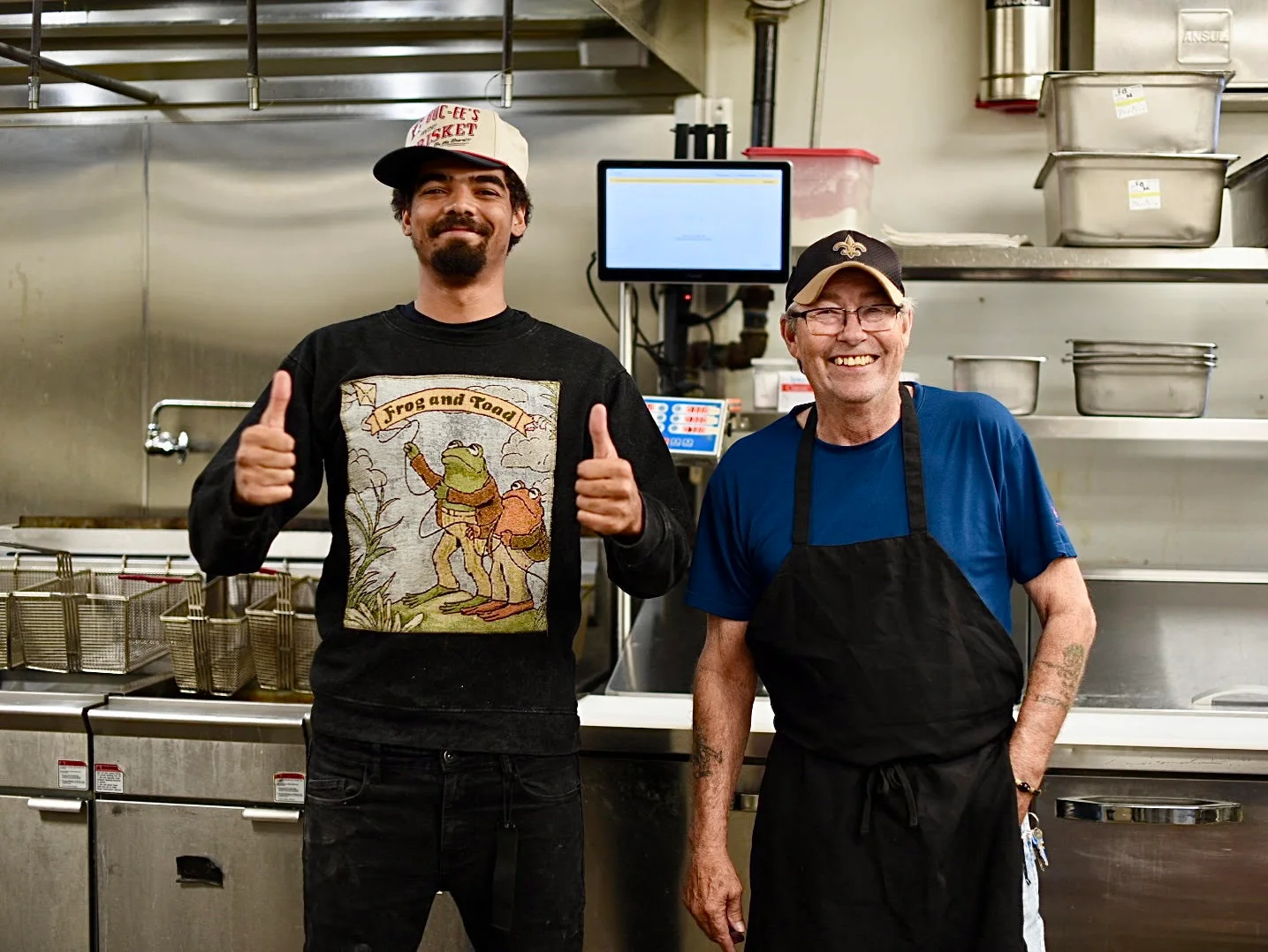 Two chefs smiling in a restaurant kitchen with cooking equipment in the background