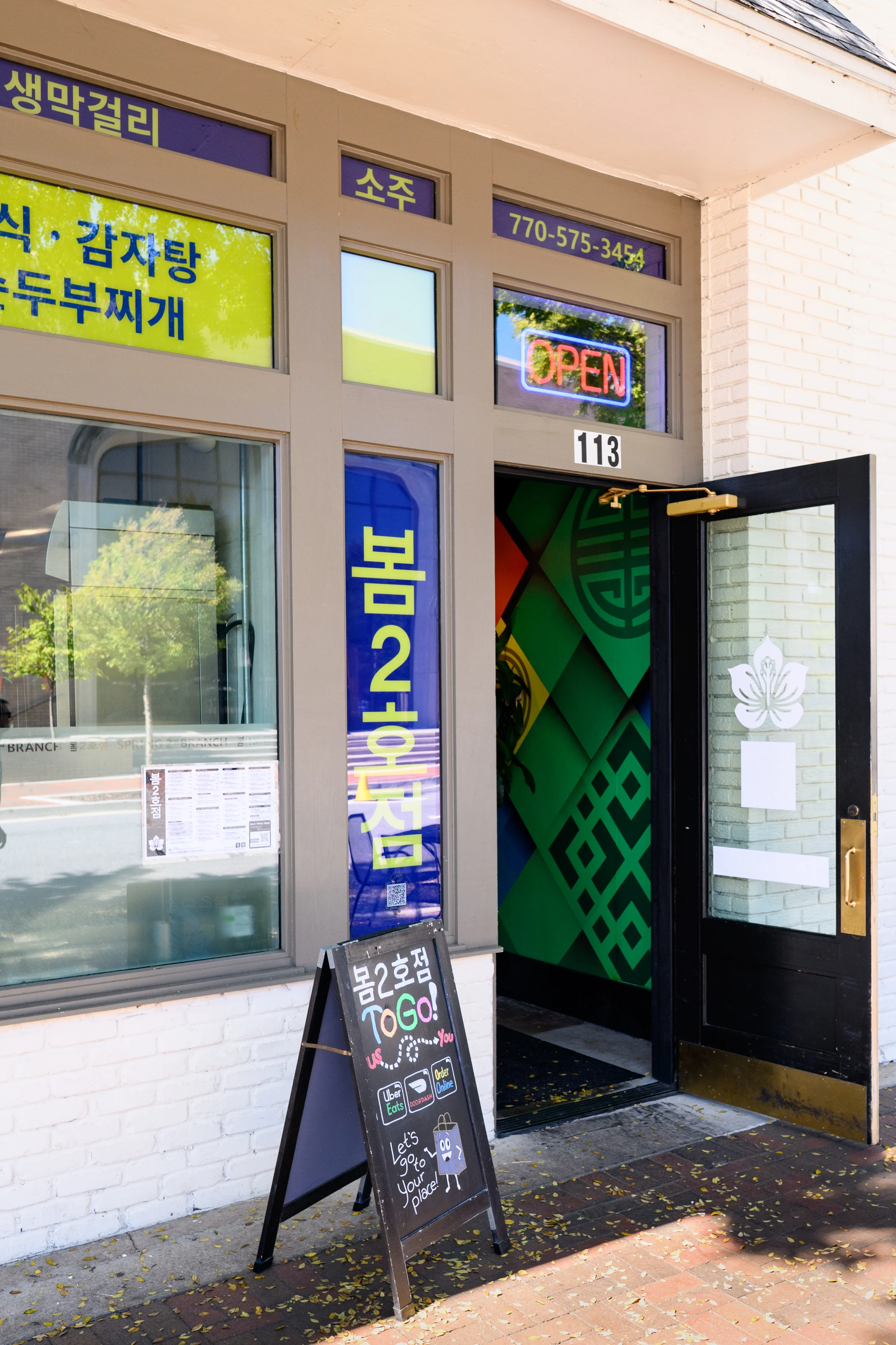 Exterior view of a Korean restaurant with vibrant signage and open hours displayed