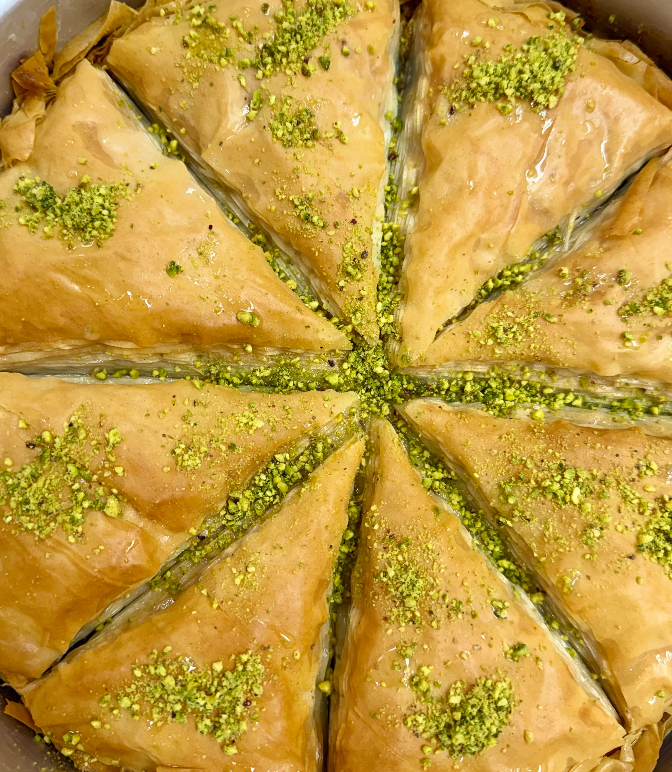 Delicious baklava topped with crushed pistachios, sliced into wedges.