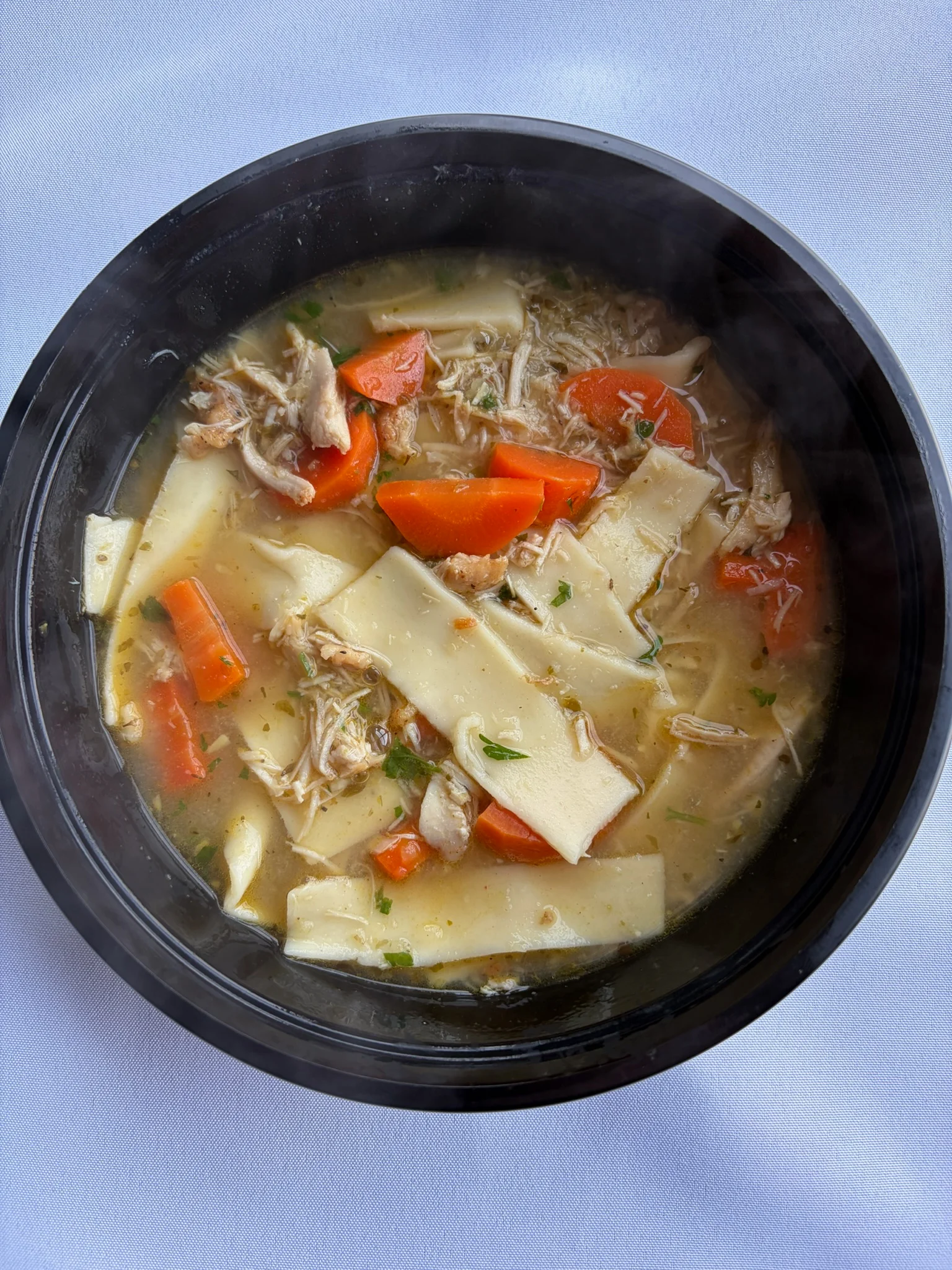 Hearty chicken noodle soup in a black bowl