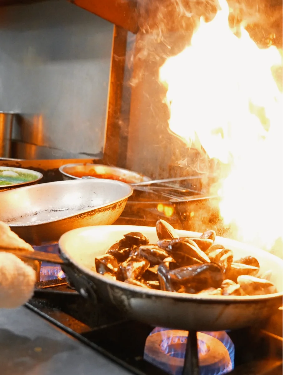 Cooking salmon fillets in a pan with vibrant sauces in the background.