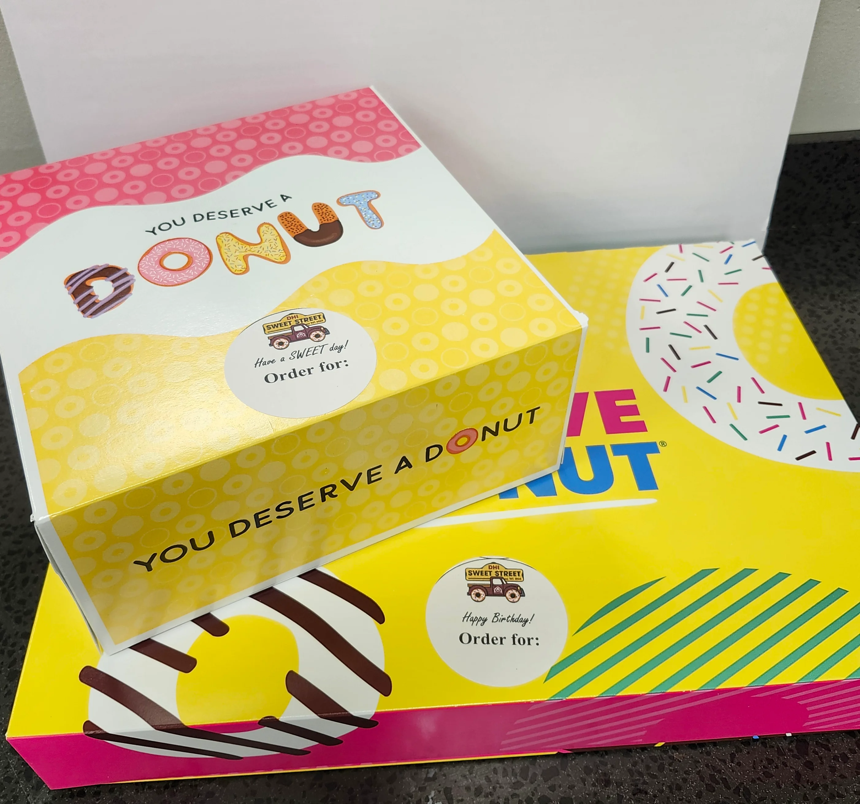 Two stacked colorful donut boxes "You deserve a donut" with Sweet Street logo DoorDash stickers.
