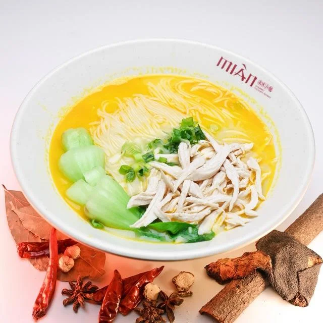 Bowl of golden chicken noodle soup with vegetables and herbs