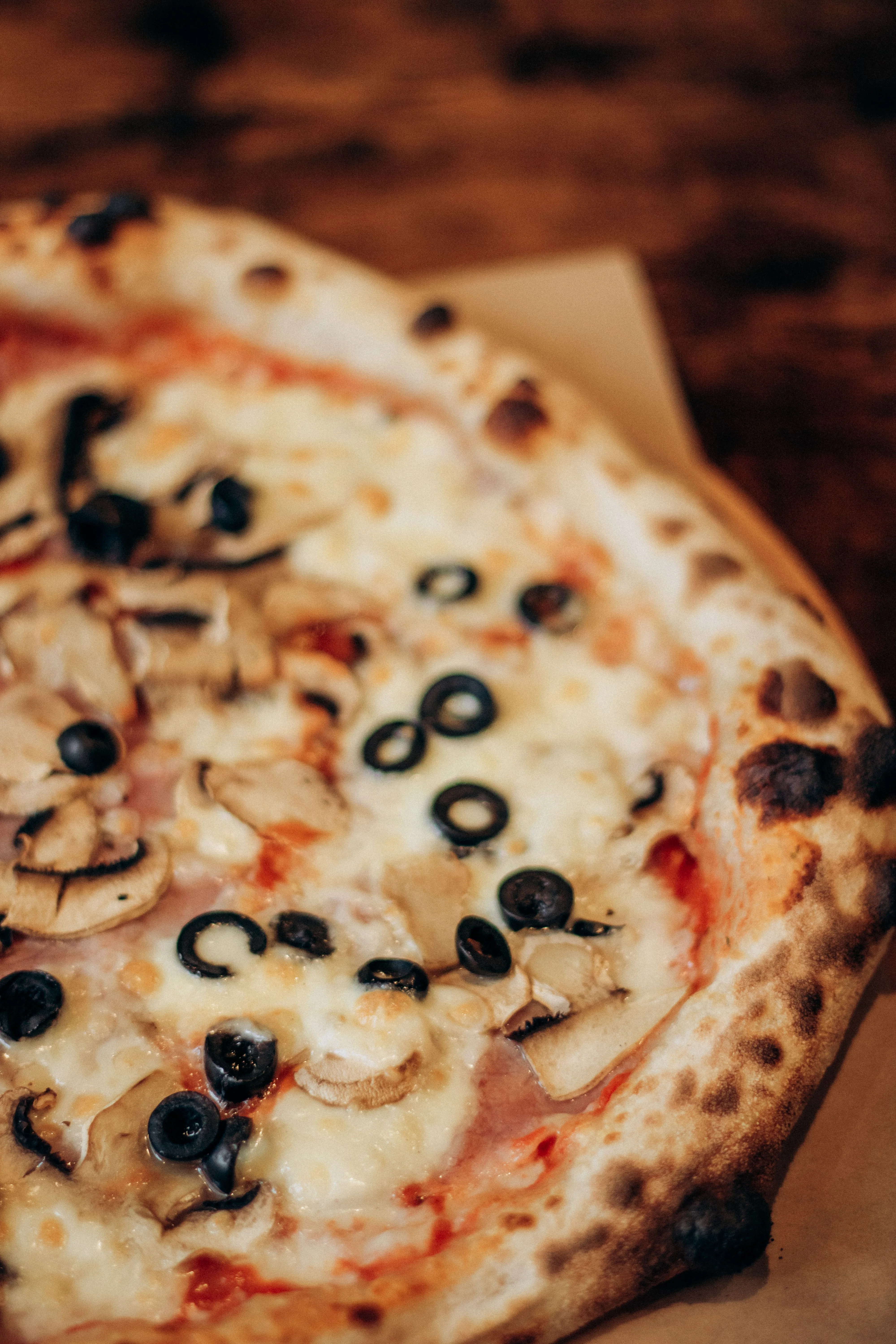 Blurred pizza topped with olives and tomato