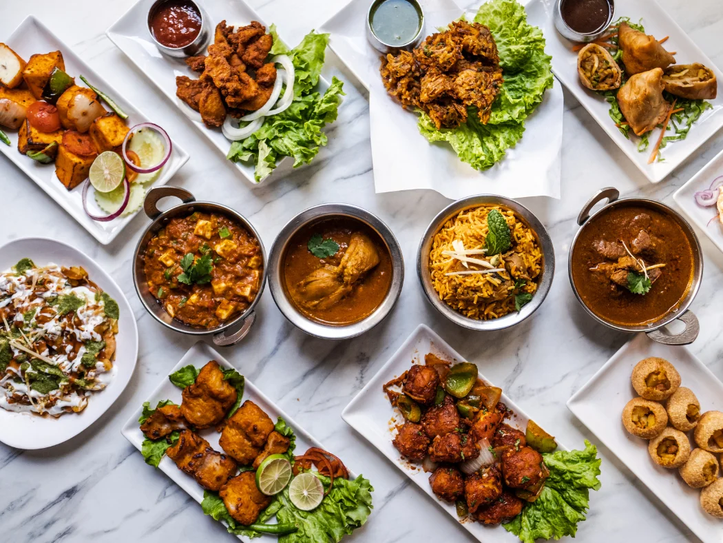 Assorted Indian dishes including biryani and samosas on a marble table