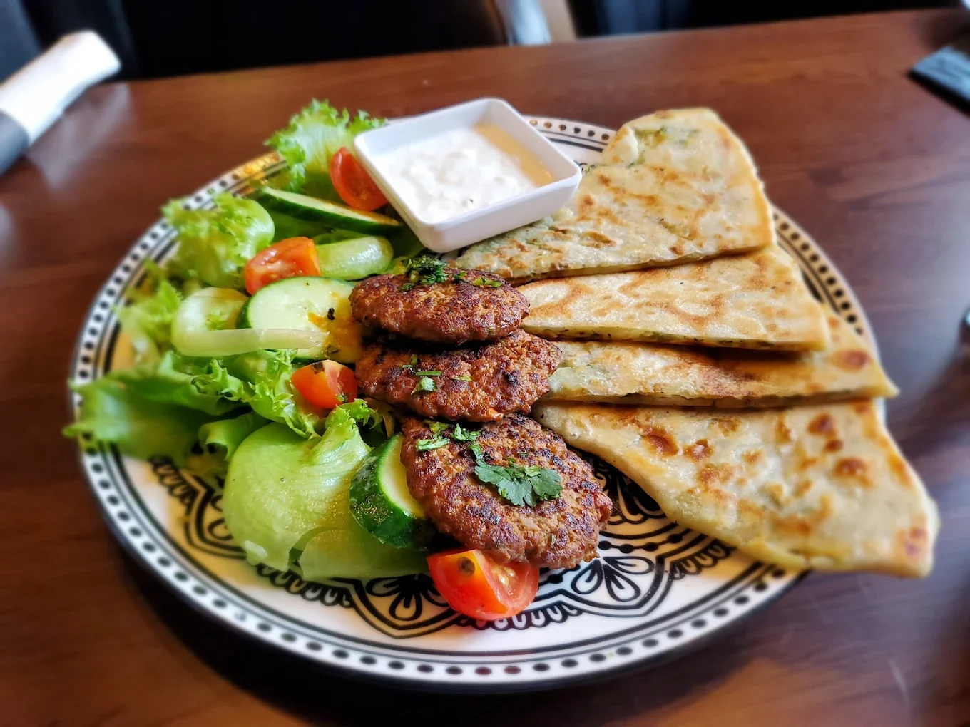 Plate of Pakistani seekh kebabs with naan and fresh salad