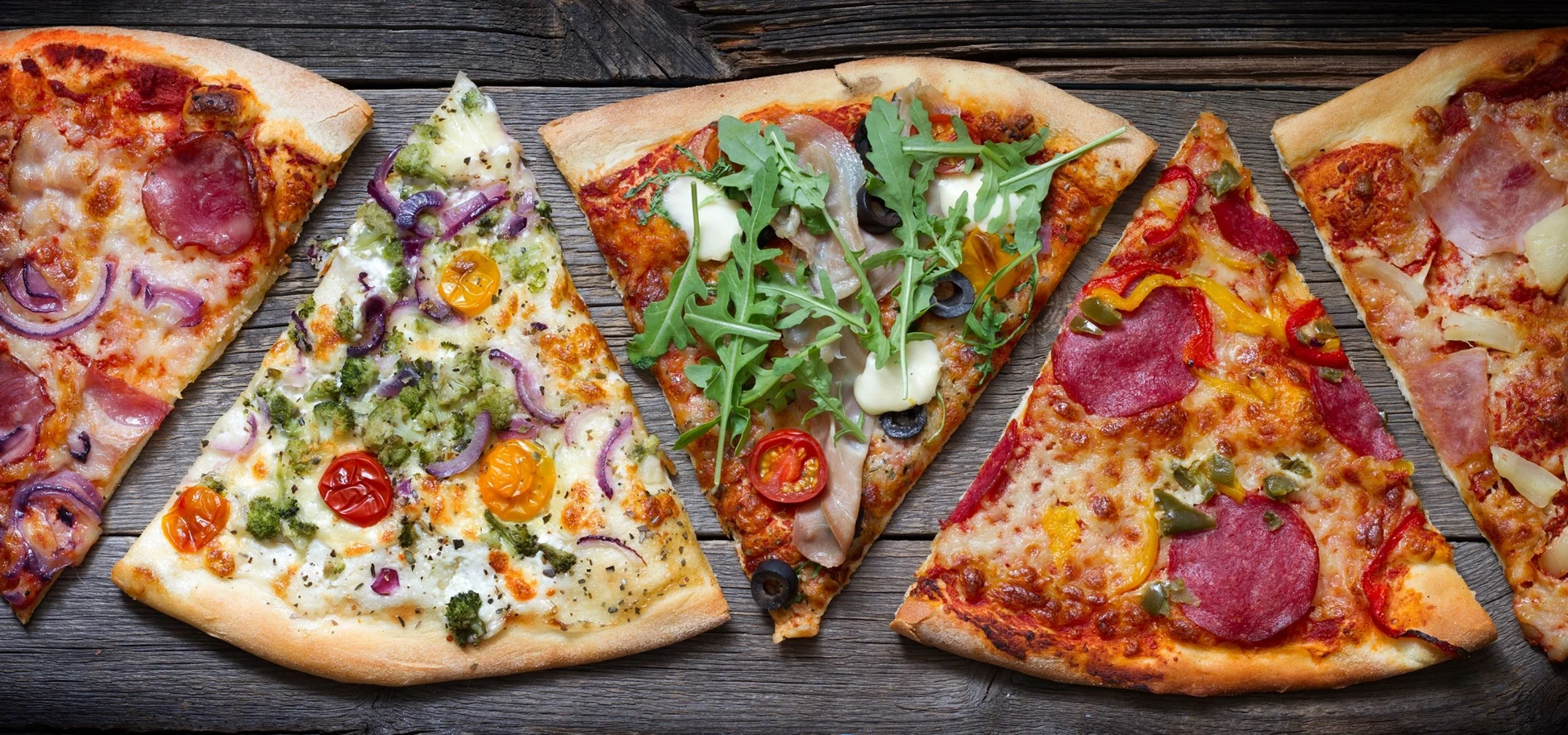 Variety of gourmet pizzas on a rustic wooden table