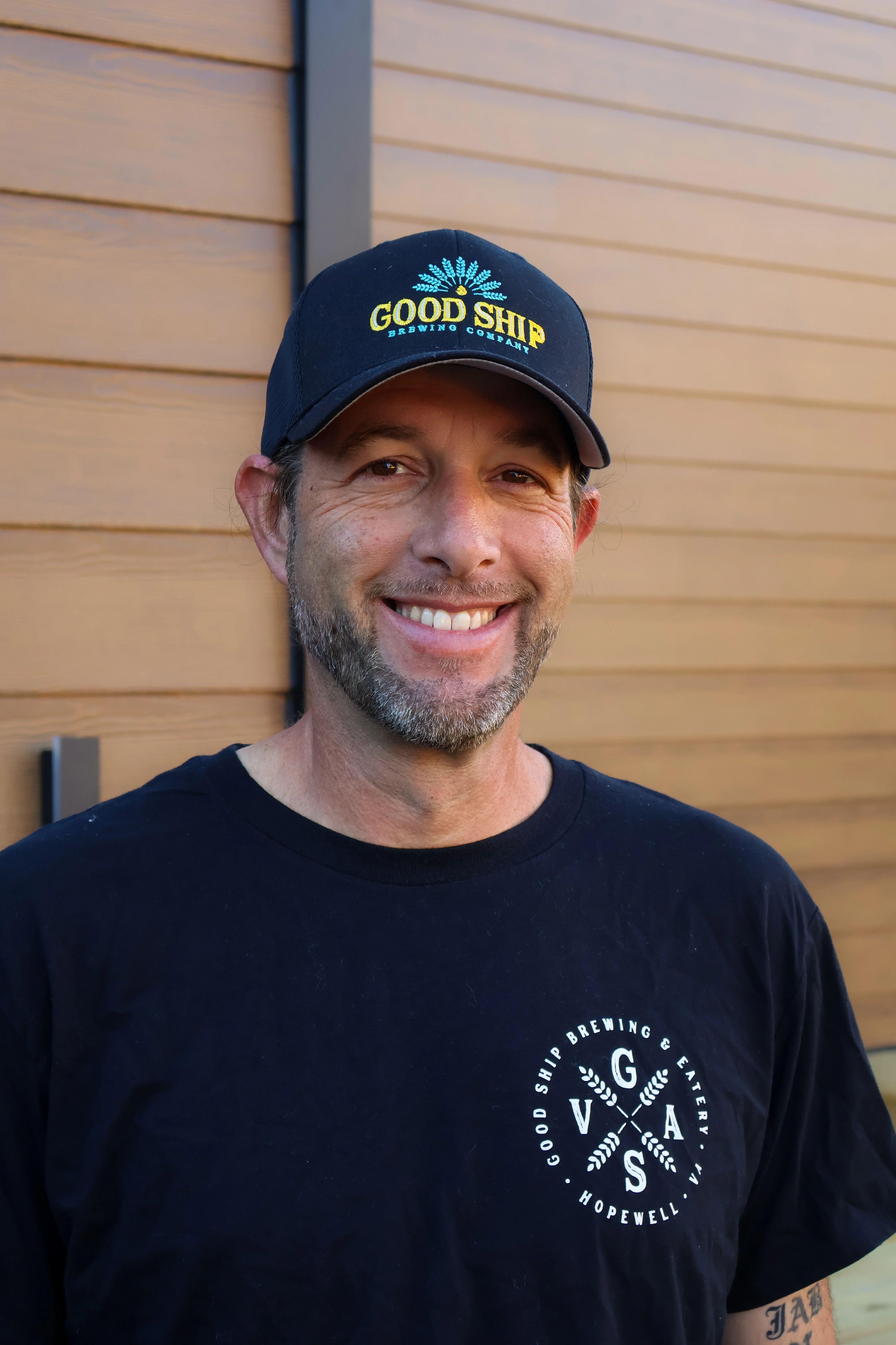 Smiling man wearing a Good Ship Brewing Company cap and shirt