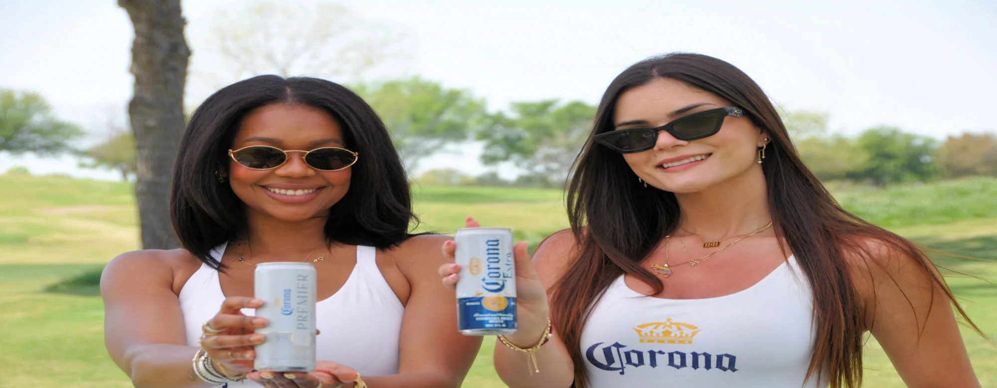 Two women enjoying beer outdoors in a sunny park