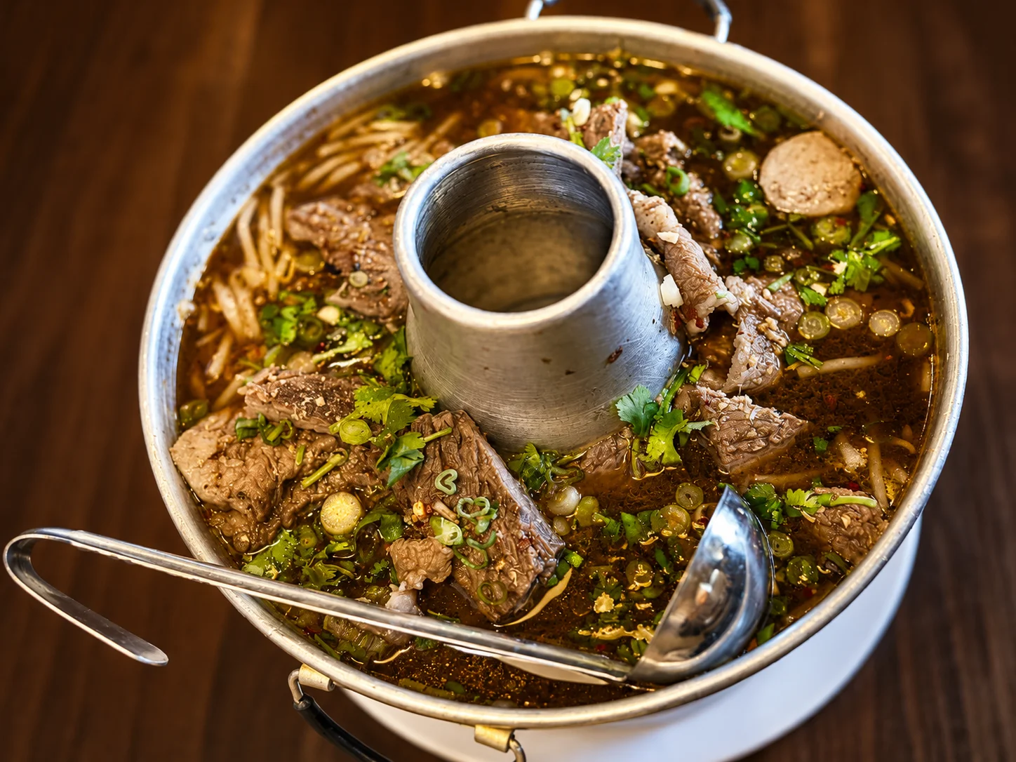 Spicy Thai beef boat noodle soup served in a traditional pot