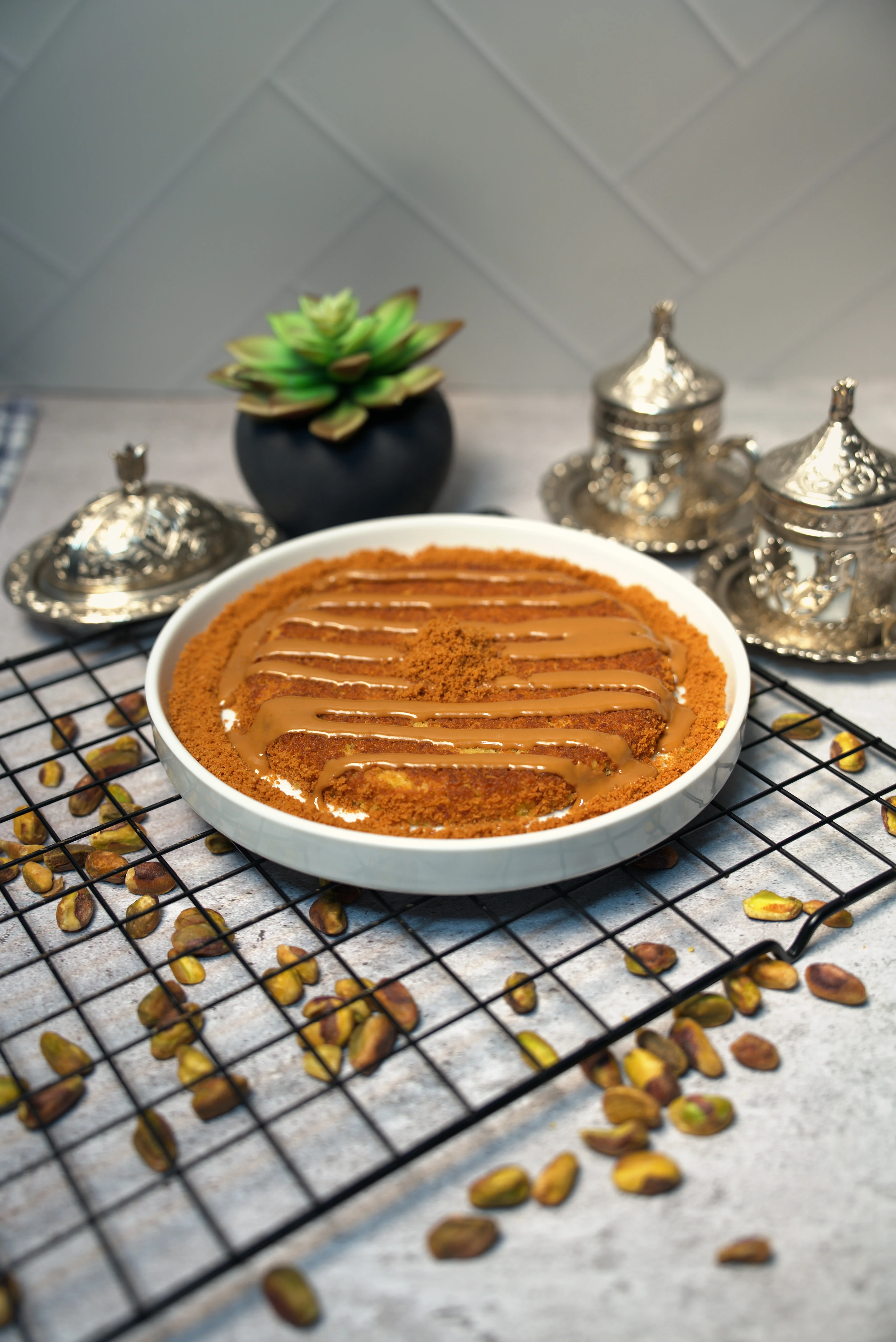 Caramel-drizzled layered dessert with pistachios on a white plate