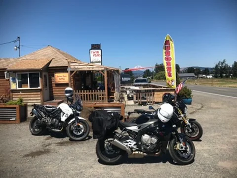 Motorcycles parked outside a rustic cafe on a sunny day