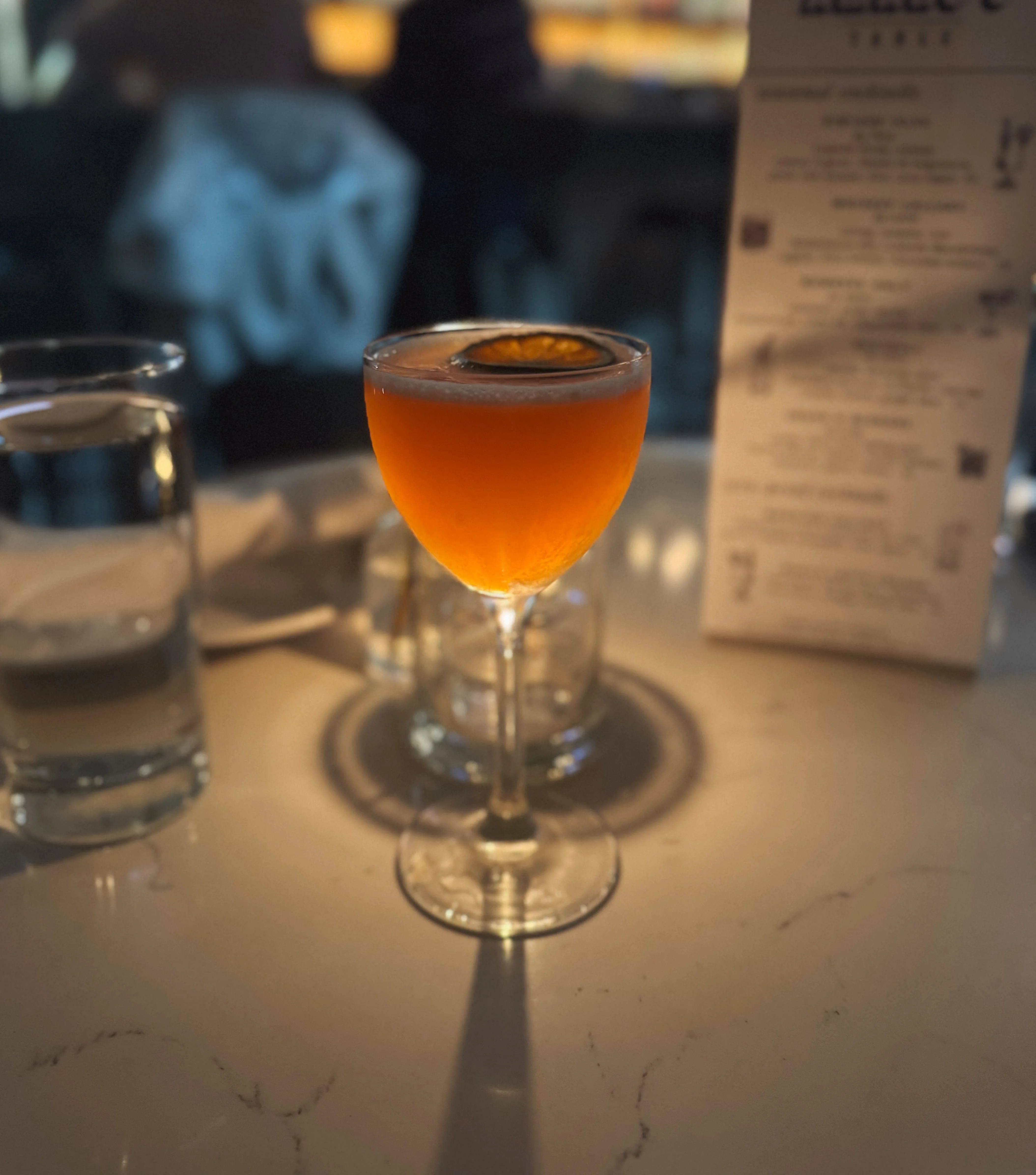 Craft cocktail with orange garnish in a stylish bar setting