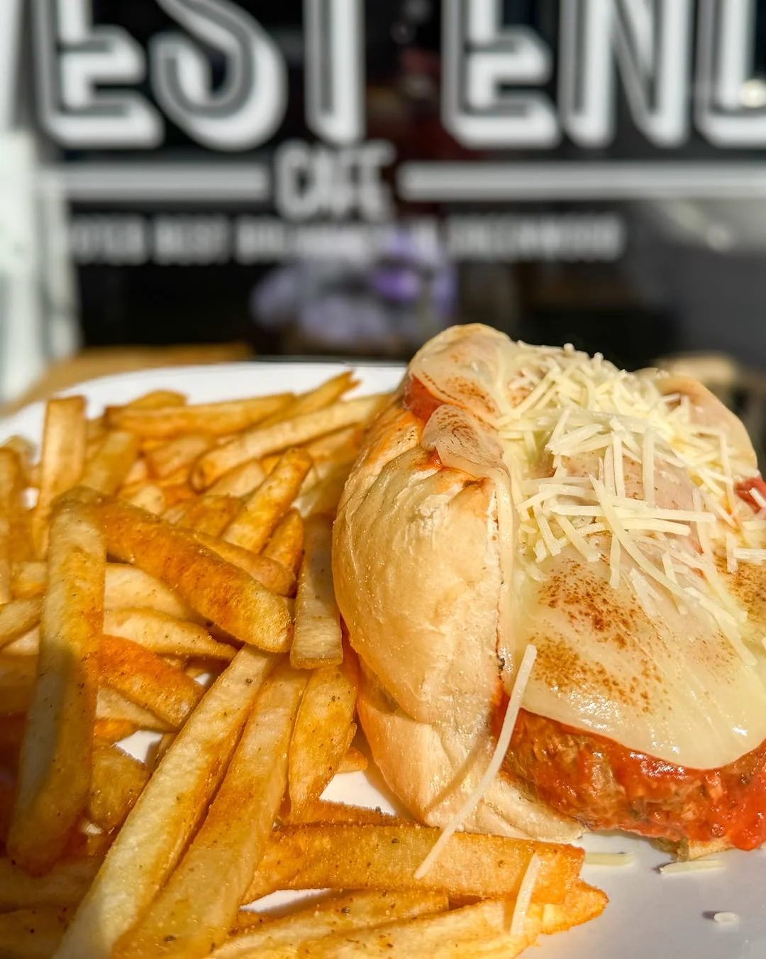 A delicious meatball sub served with melted cheese and marinara sauce, accompanied by crispy golden fries.