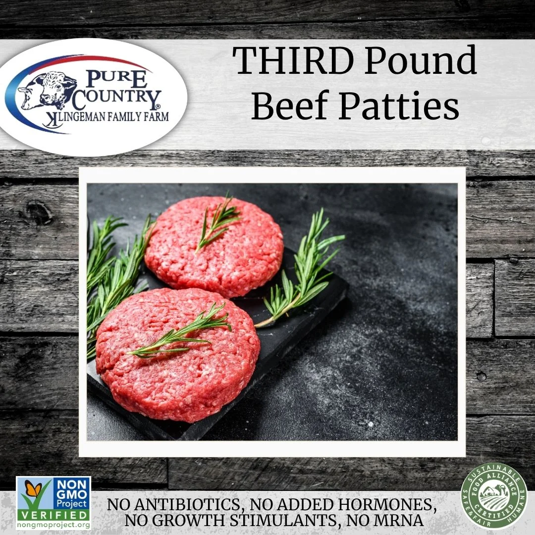 Raw beef patties on a slate board with fresh herbs