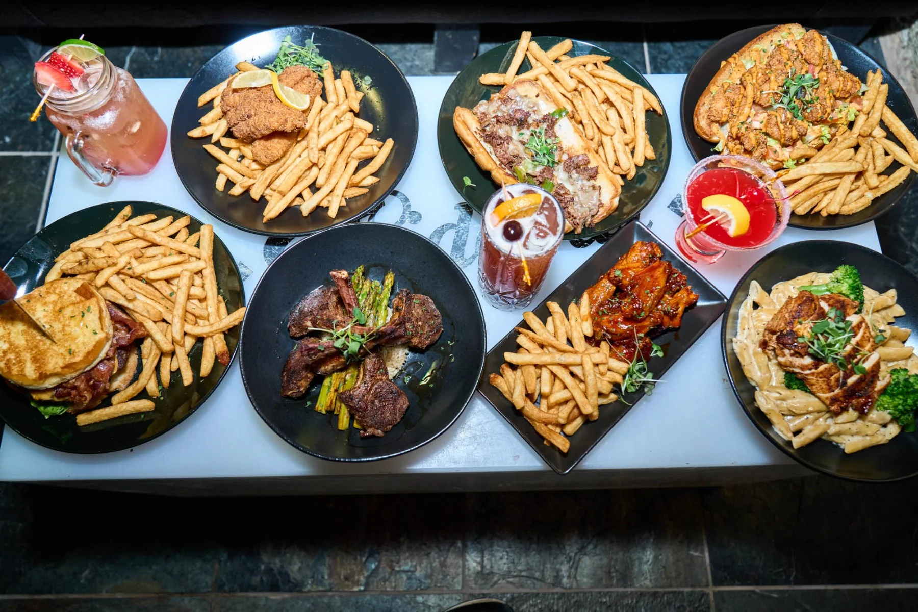 Assorted American dishes with fries and cocktails on a table