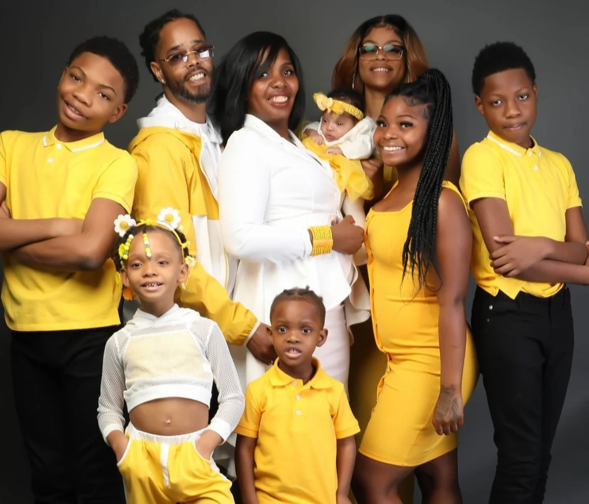 Family portrait in matching yellow outfits against a gray background