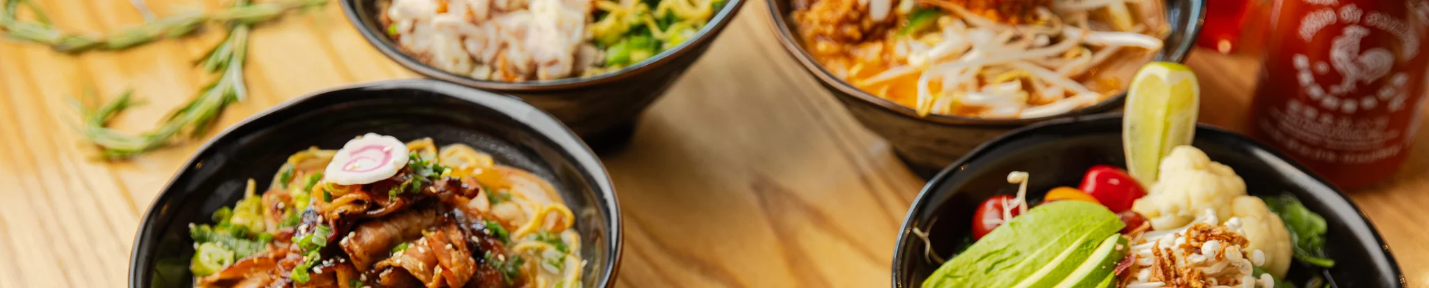 Assorted Asian noodle bowls with fried chicken and fresh vegetables