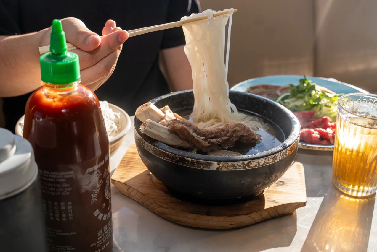 Bowl of Vietnamese pho with beef and fresh herbs in a cozy setting