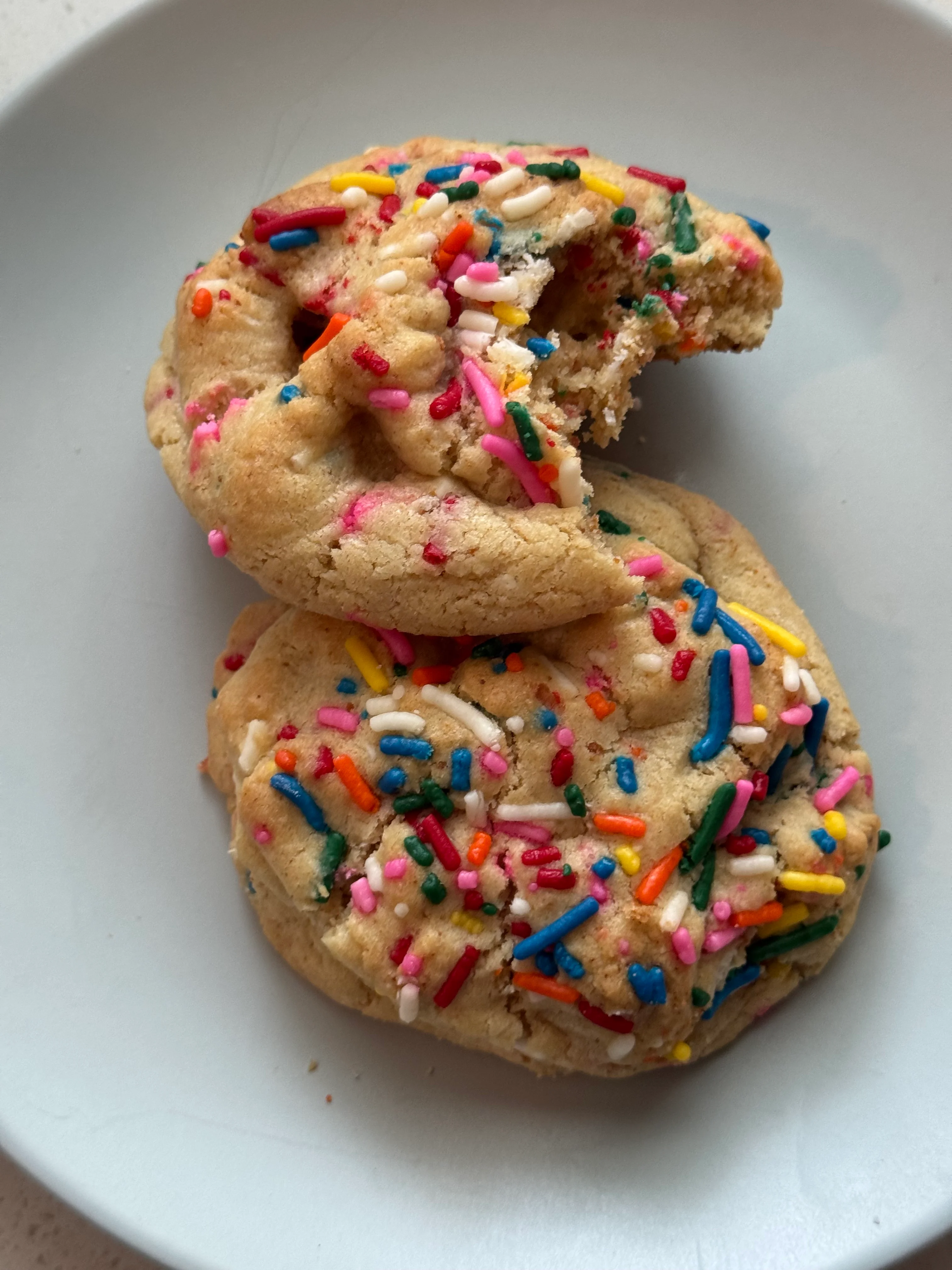 Smiling person holding a freshly baked cookie in a modern kitchen