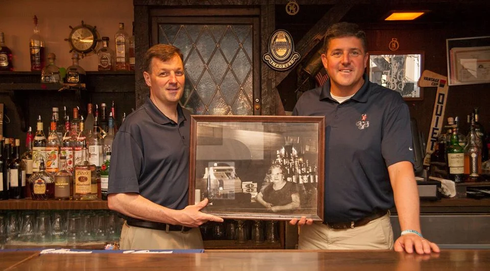 Bartenders holding a vintage photo in a cozy bar setting