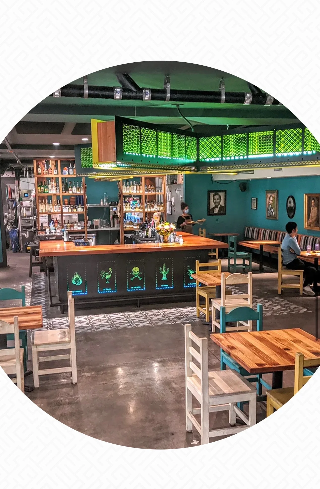A modern restaurant interior showcasing a bar area with colorful decor and wooden tables.