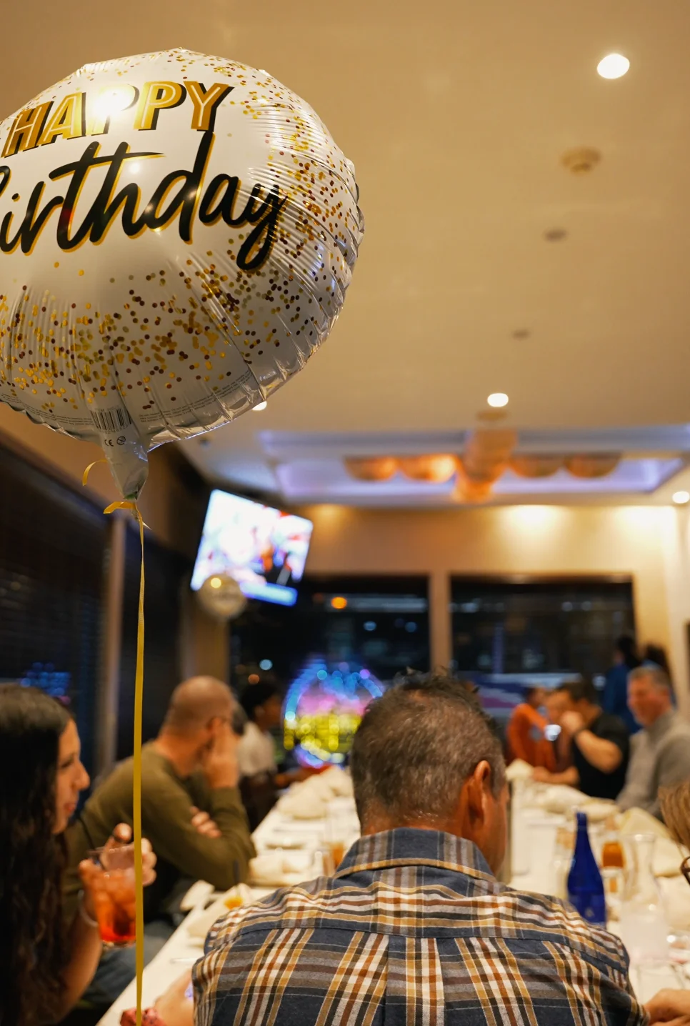 Birthday celebration with a 'Happy Birthday' balloon in a restaurant setting.