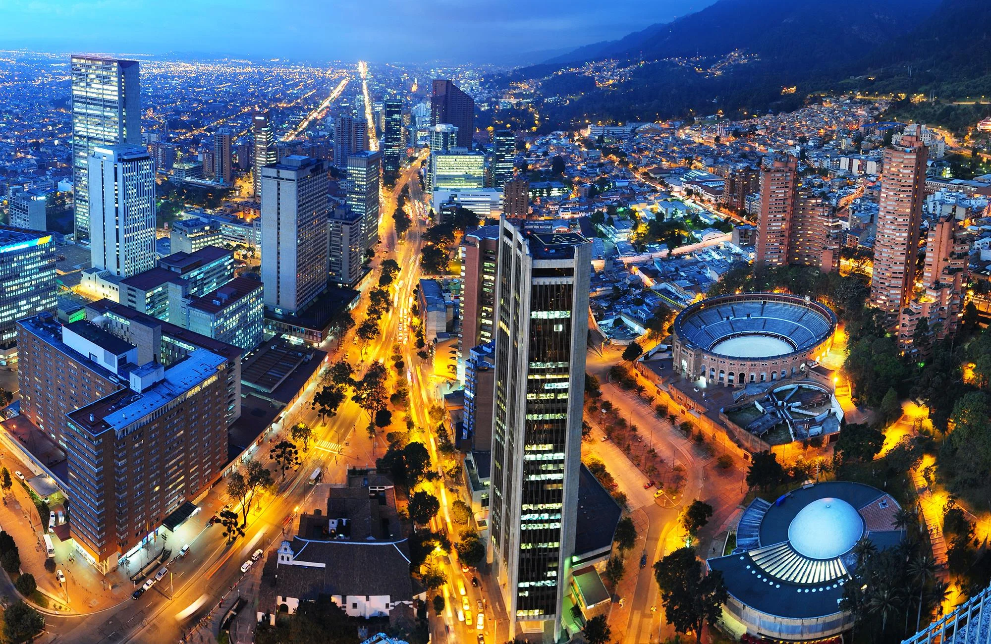 A stunning aerial view of a city at dusk, showcasing illuminated buildings, streets, and landmarks, capturing the vibrant urban landscape.