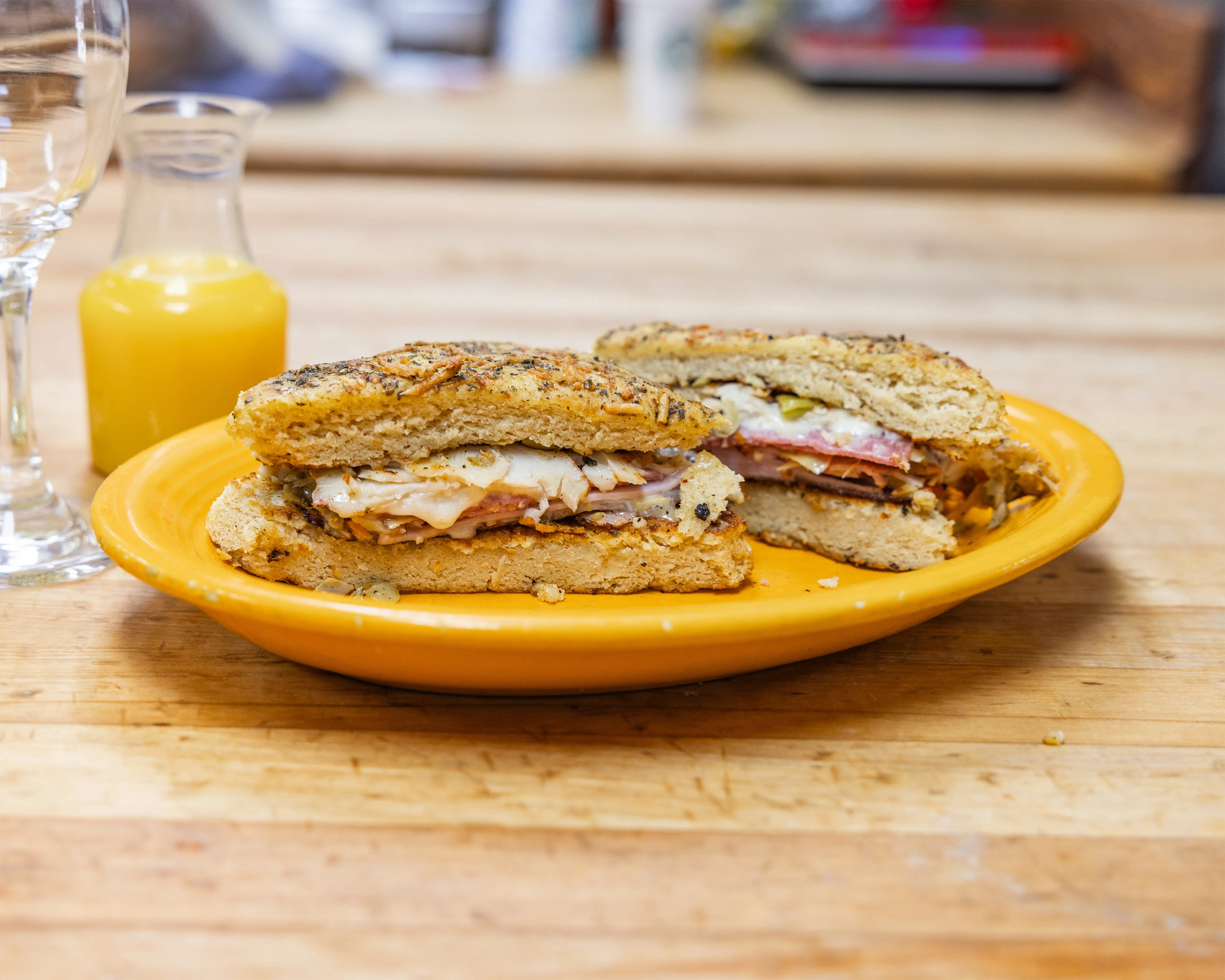 Grilled Italian panini with deli meats and cheese on a yellow plate