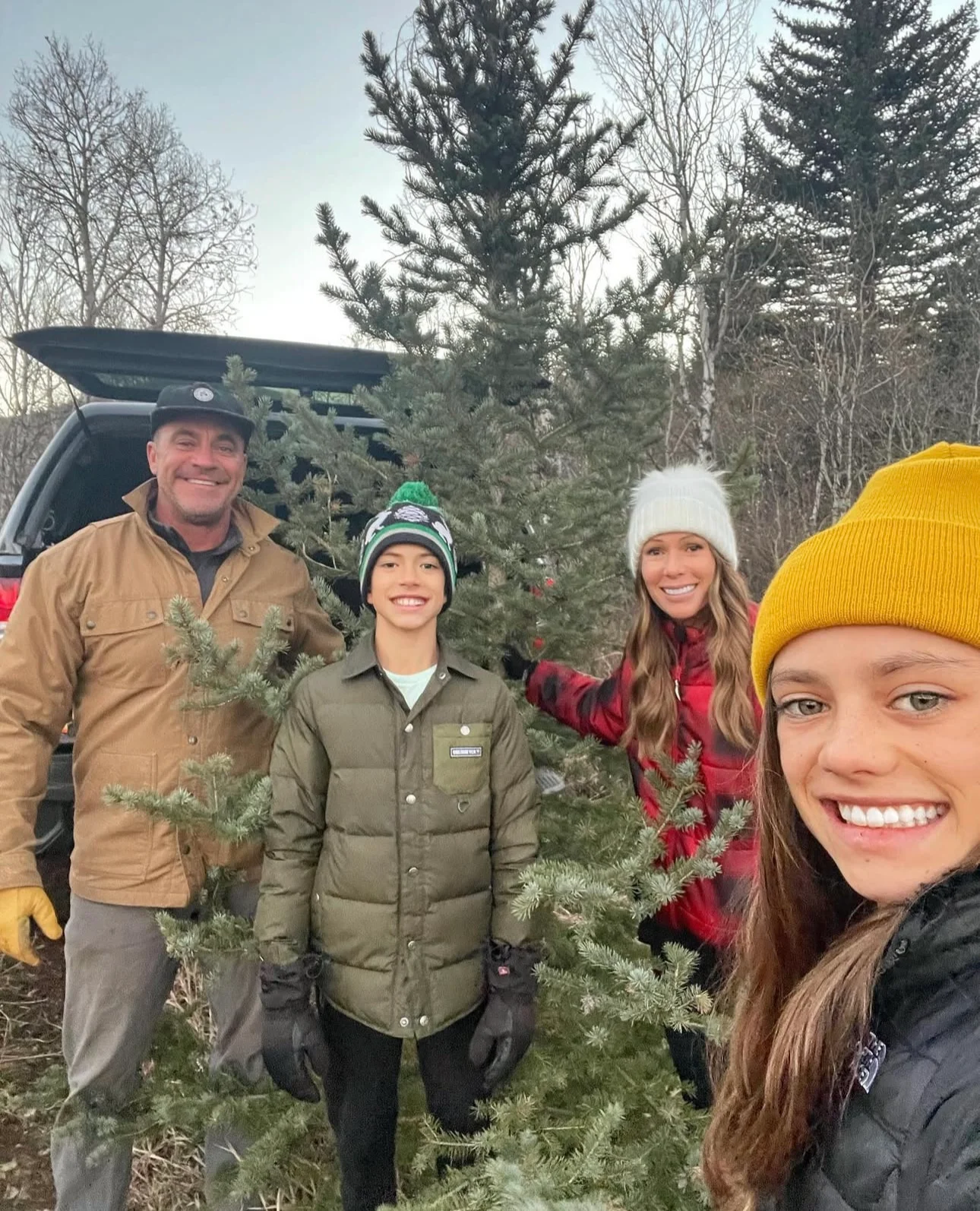 Family posing with a freshly cut Christmas tree outdoors