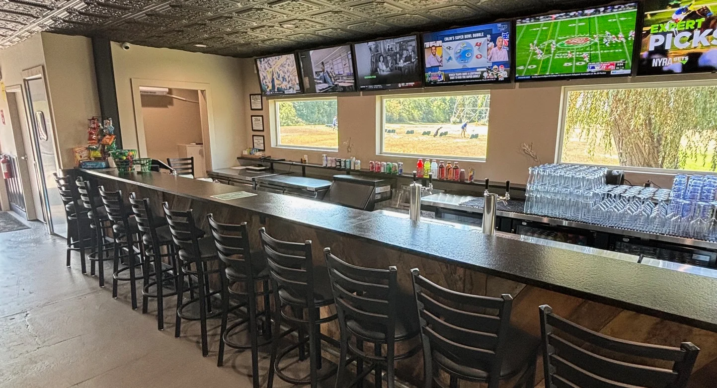Modern bar interior with black stools and multiple TVs