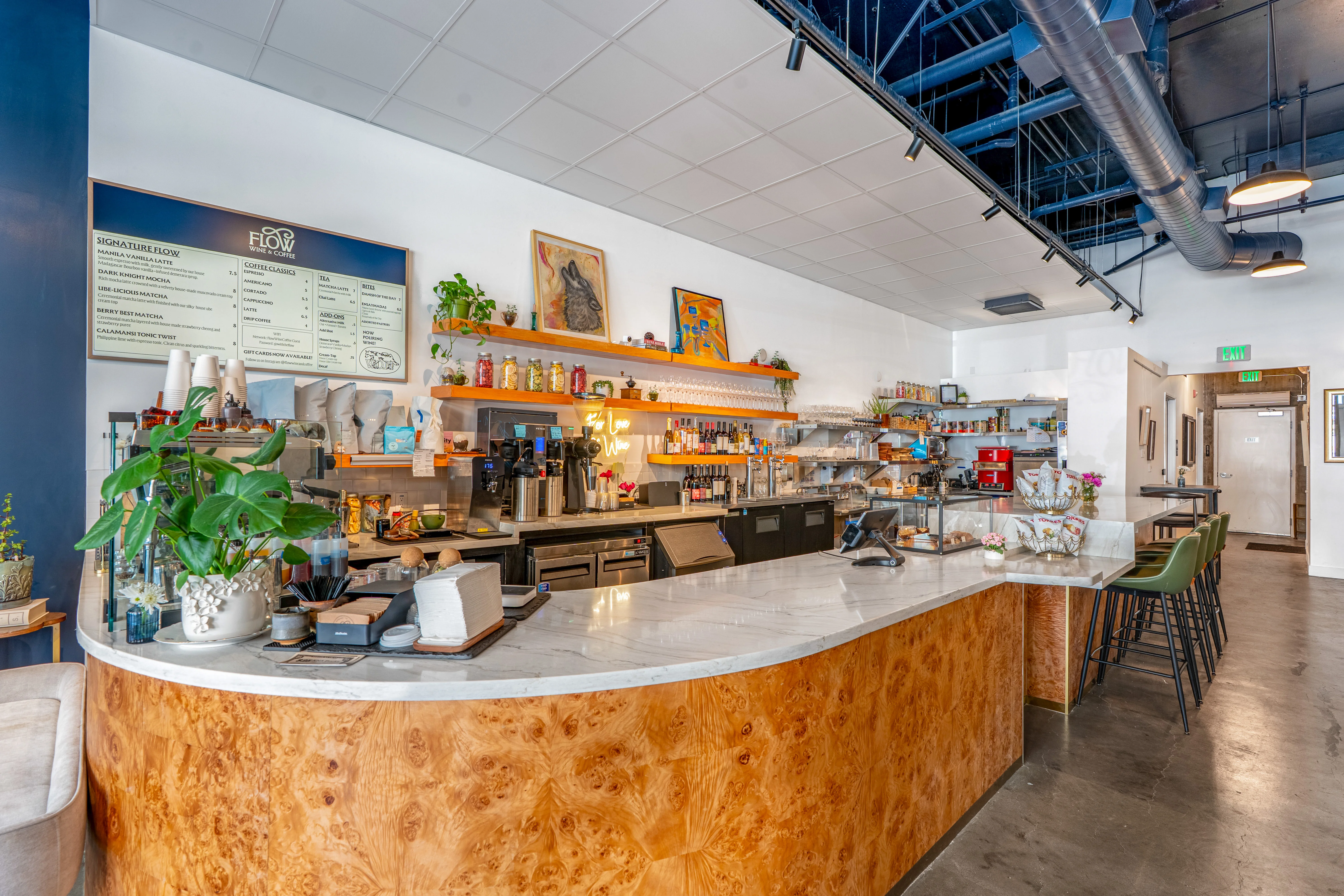 Interior of a modern café with tables, artwork, and a drink special sign.