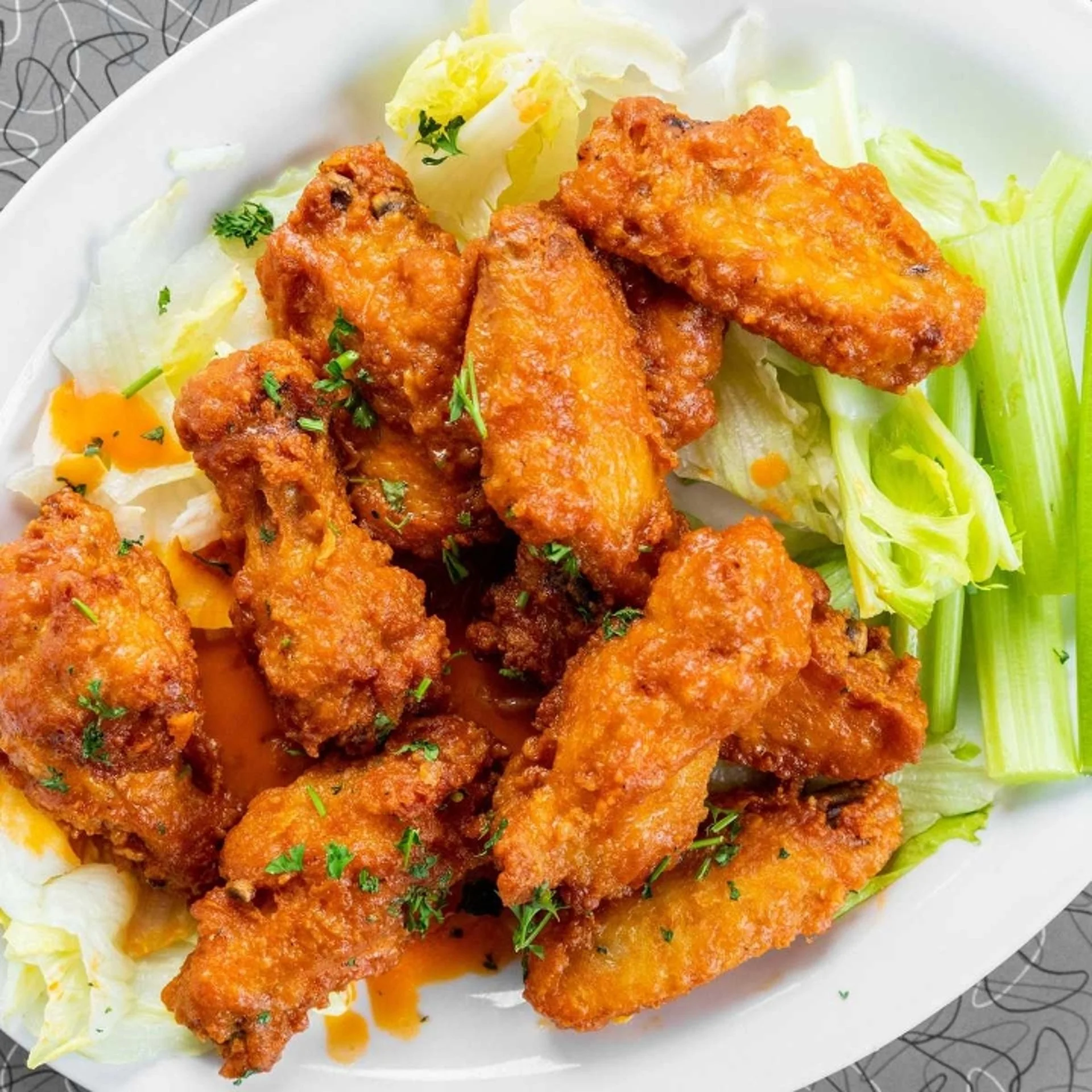 Crispy chicken wings served with fresh celery, perfect for parties and catering.