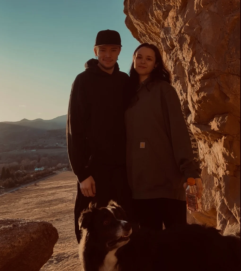Couple posing with a dog at sunset in a scenic outdoor location