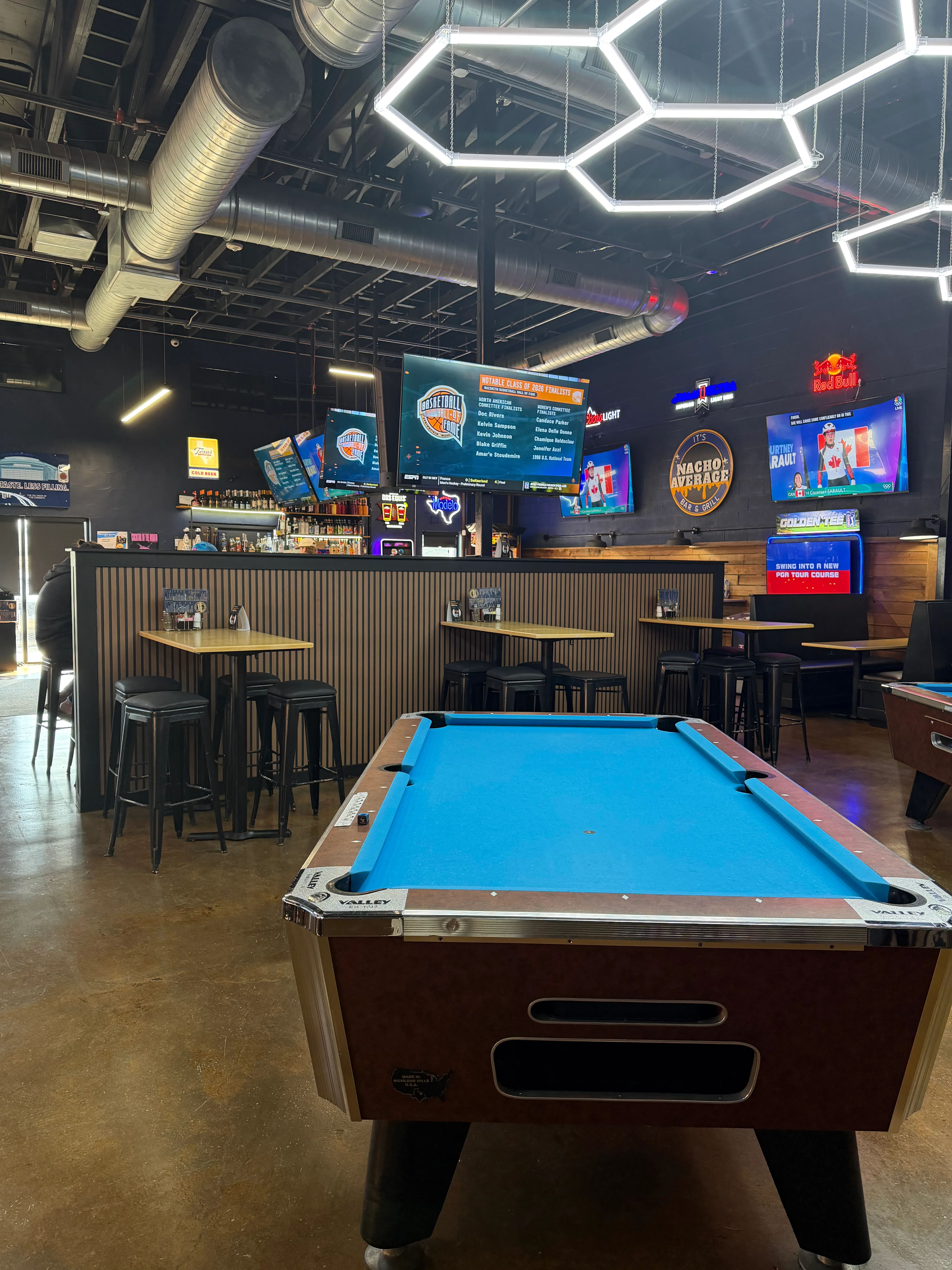 Modern bar interior with pool table and multiple screens