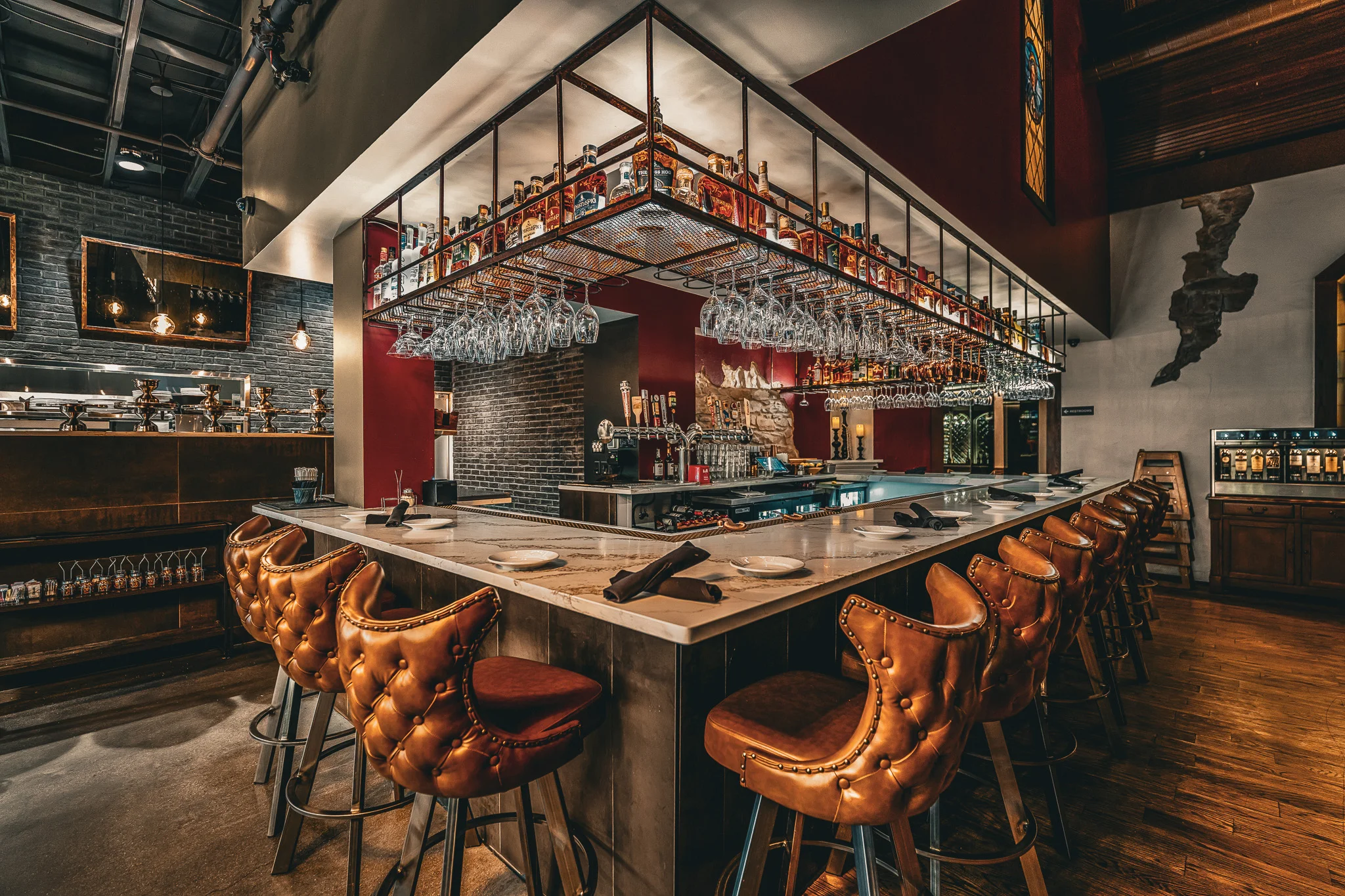 Upscale restaurant bar interior with leather bar stools and hanging glassware