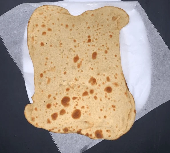 Different type of naan bread on white parchment paper.