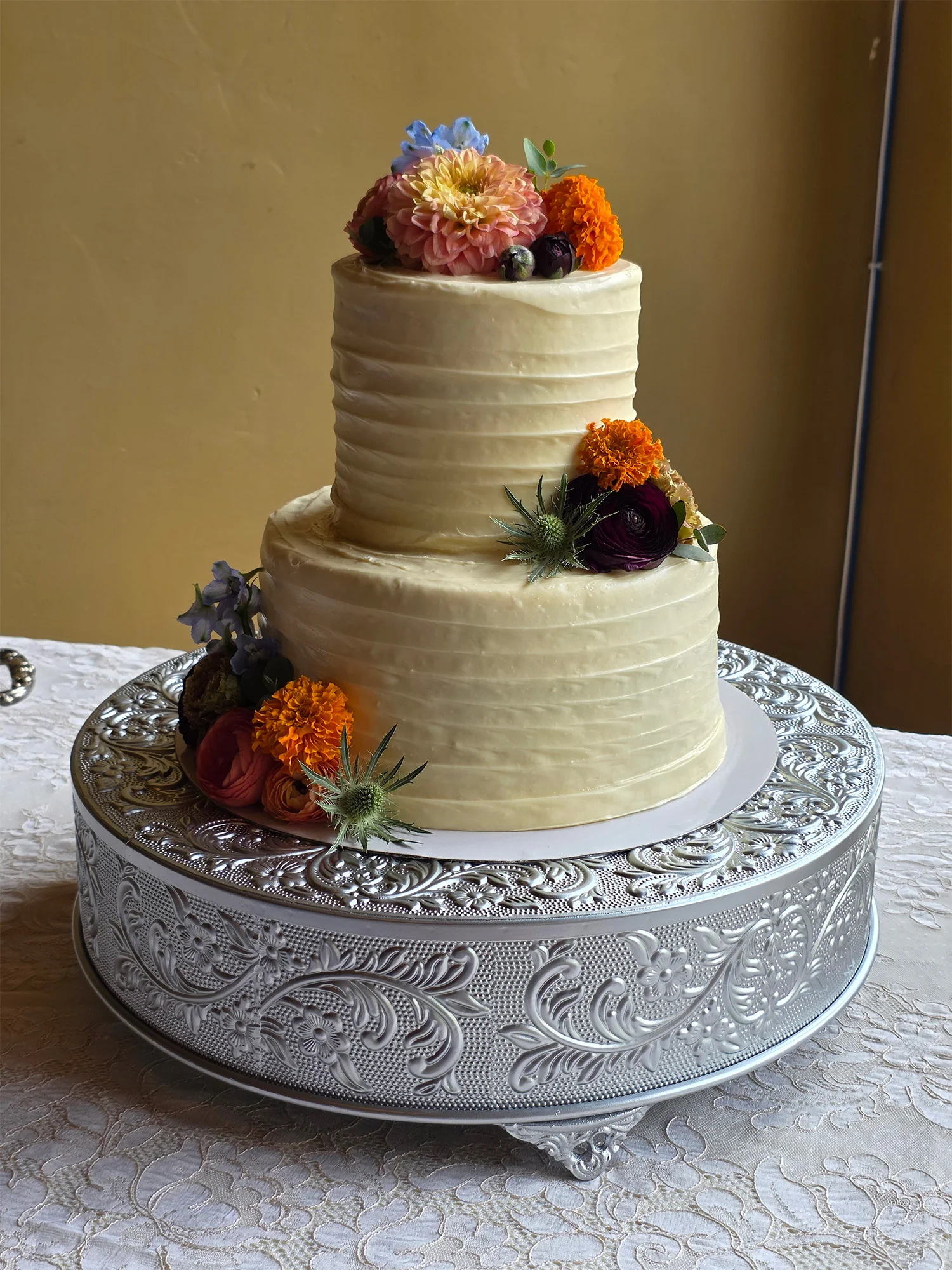 Three-tier wedding cake decorated with colorful fresh flowers