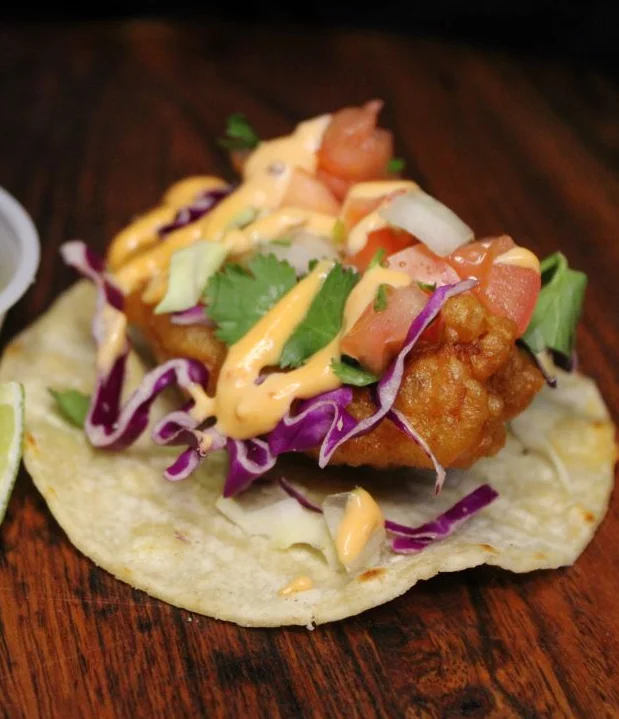 Delicious fish taco topped with fresh ingredients and served on a plate.