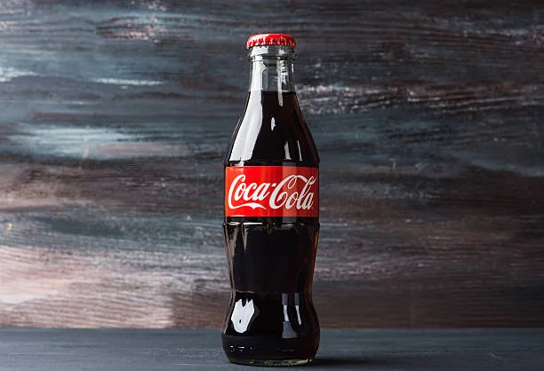 Classic glass bottle of Coca-Cola on a wooden surface