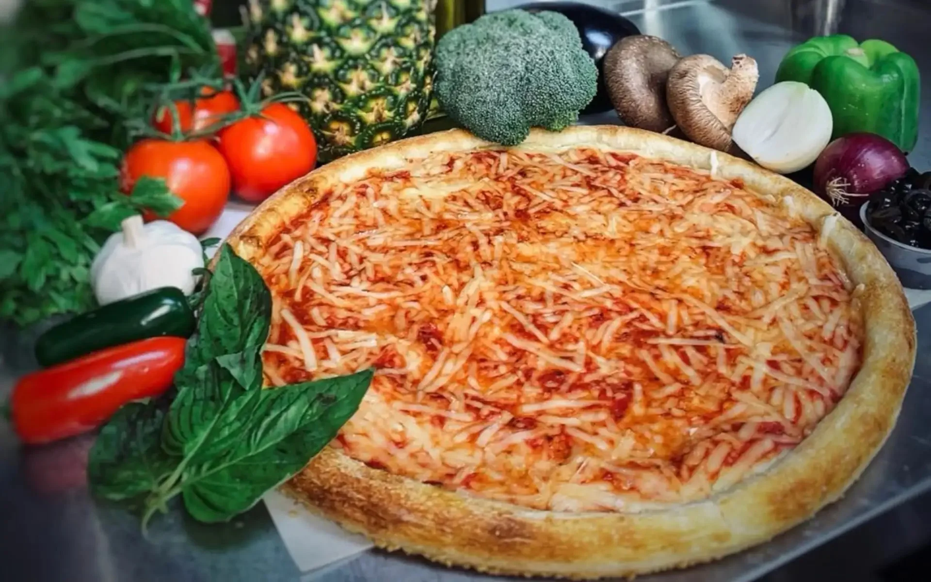 Pizza surrounded by tomatoes, basil, peppers, mushrooms and other vegetables