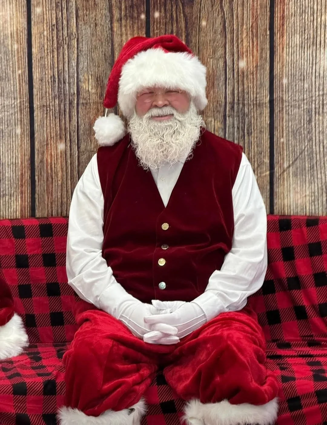 Jolly Santa Claus in festive attire sitting on a cozy plaid couch
