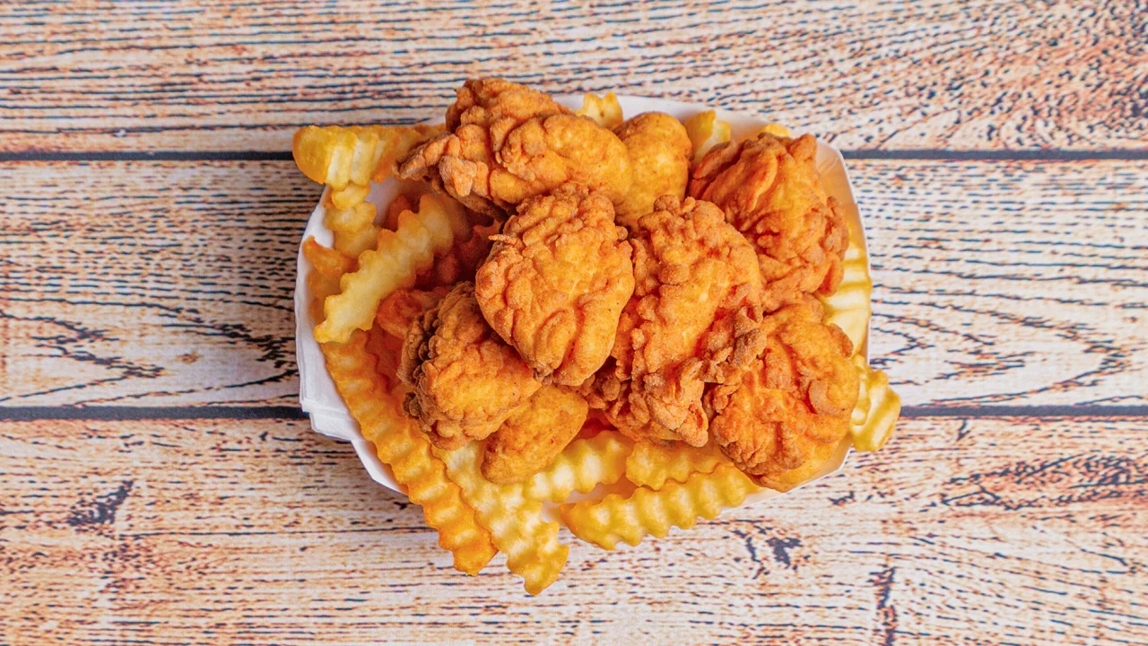 A bowl filled with fried chicken pieces and crinkle fries, offering a hearty meal option.