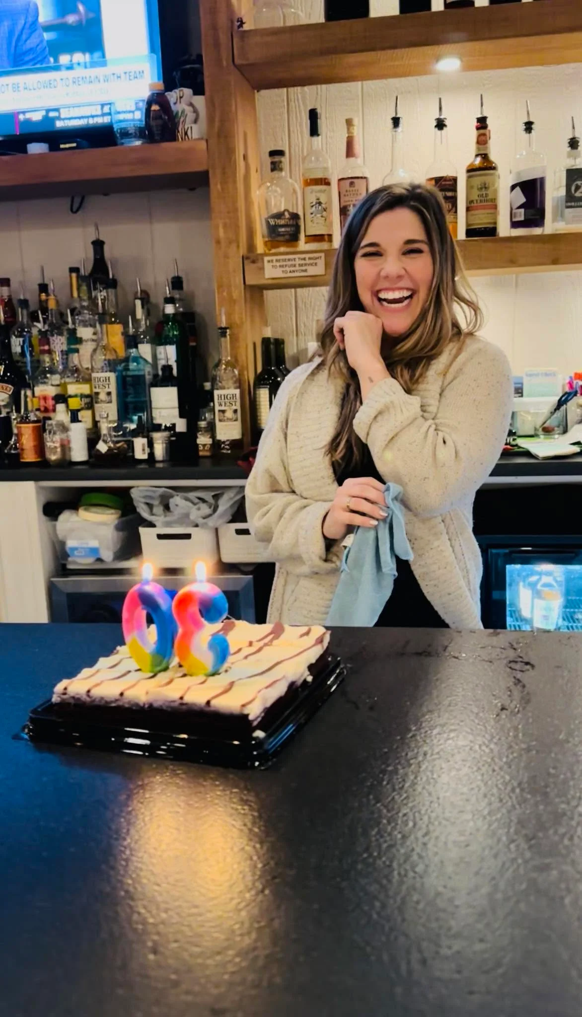 Smiling bartender celebrating with a birthday cake at a lively bar