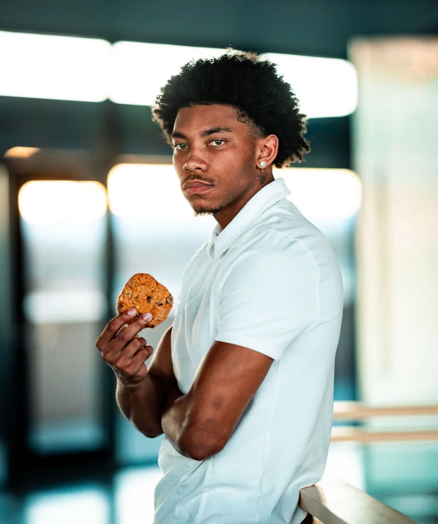 Young man holding a chocolate chip cookie in a modern setting