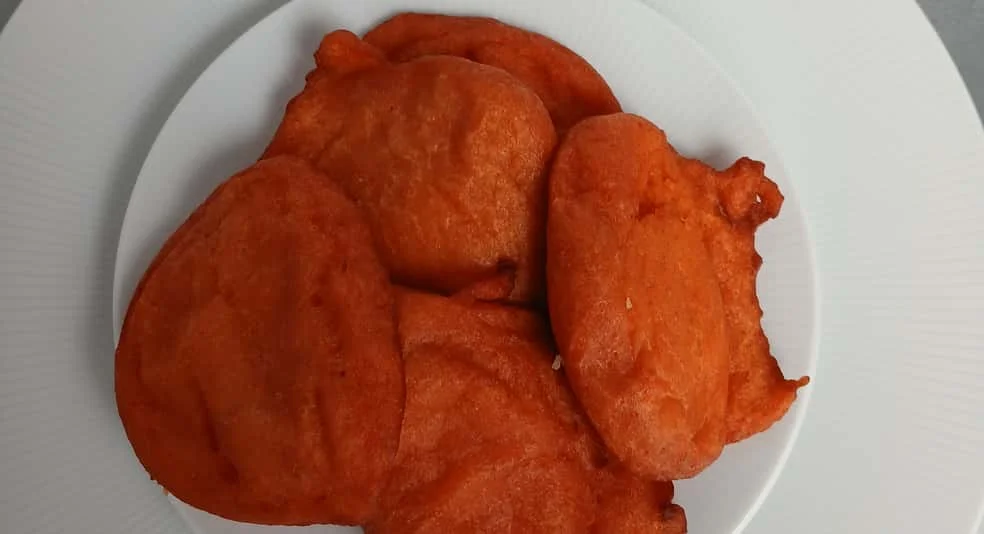 Vibrant Jamaican festival dumplings on a white plate