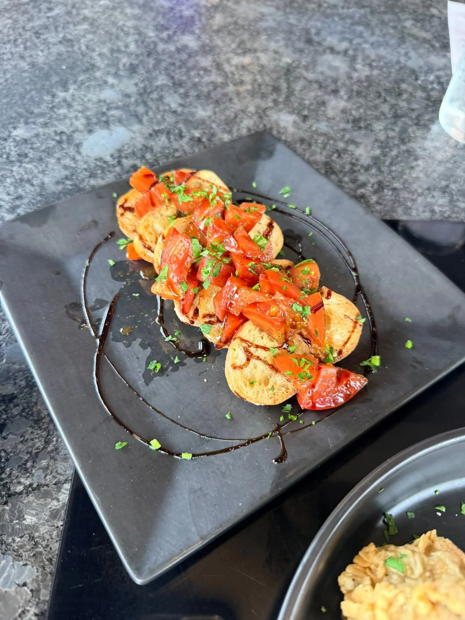 Bruschetta with fresh tomatoes and herbs on a black plate