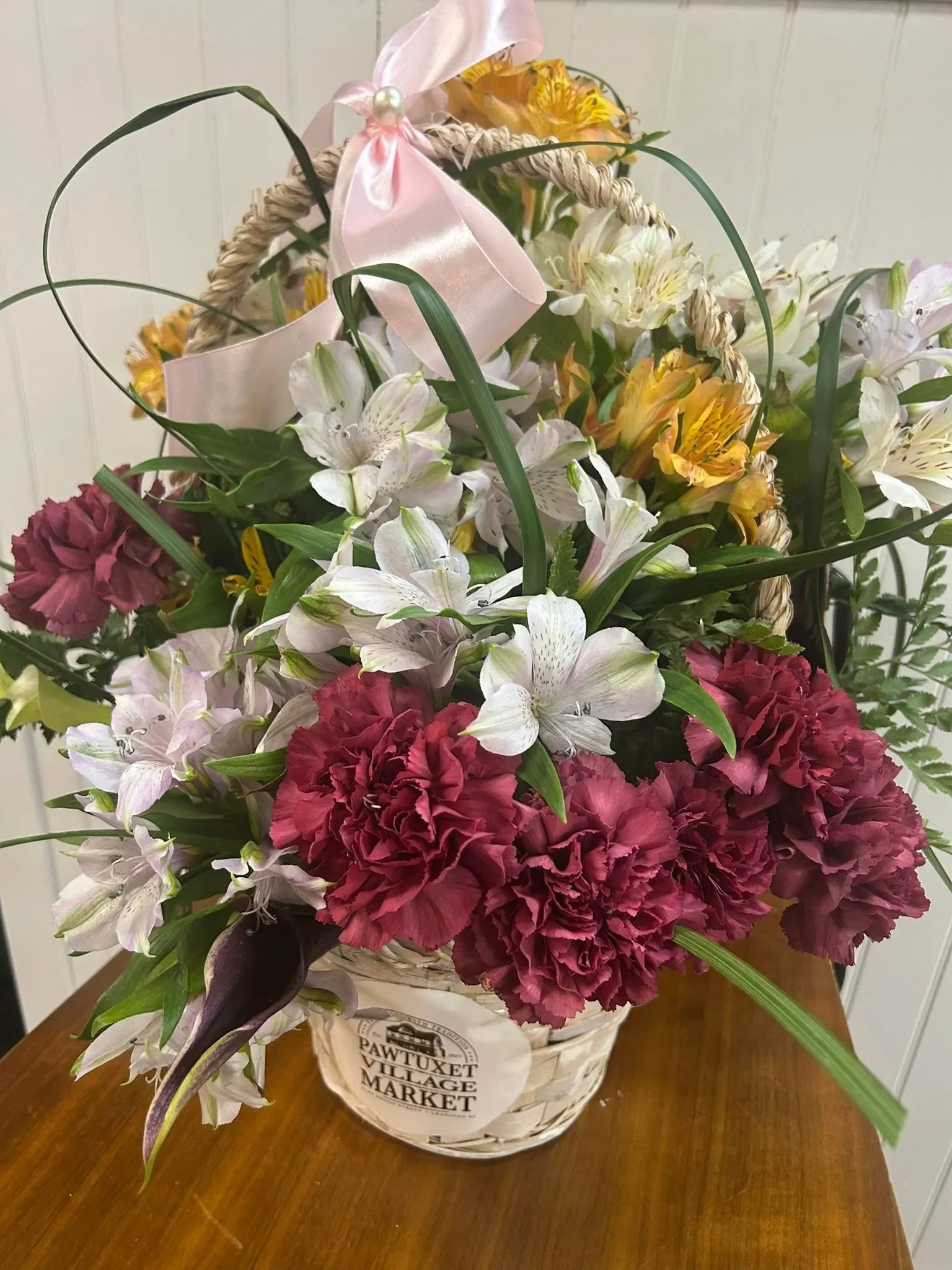 A beautiful custom floral arrangement from Pawtuxet Village Market featuring white hydrangeas and deep red roses in an elegant black basket.